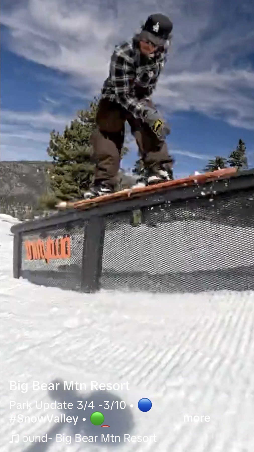 Snowboarder in black pants, long sleeve, and hat riding their board on a ThirtyTwo down rail in the terrain park on a sunny winter day.